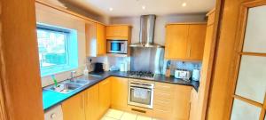 cocina con armarios de madera, fregadero y ventana en Cosy 2 bedroom appartment with gated parking by River Thames en Kingston upon Thames