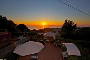 a sunset over a patio with umbrellas and the ocean at B&B Il Tramonto in Anacapri