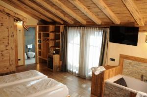 a bedroom with a bed and a television and a tub at Hotel Helvetia in Livigno