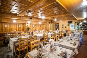 a dining room with tables and chairs with white tablecloths at Hotel Helvetia in Livigno