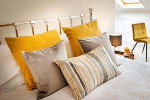 a bed with yellow and white pillows on it at Luxury Studio Apartment - Town Centre in Whitehaven