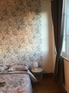 a bedroom with a bed with a floral wallpaper at Gîte spacieux et chaleureux in Sainte-Mère-Église