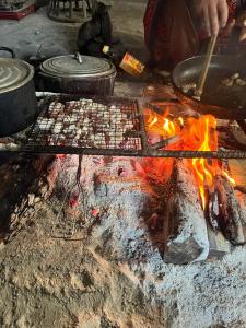 a person cooking food on a grill with fire at Hoa Phong homestay Moc Chau in Mộc Châu