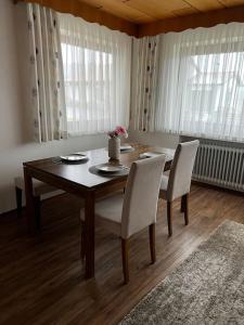 einen Esstisch mit 2 weißen Stühlen, einem Tisch und einem Chairsktop in der Unterkunft Ferienwohnung Makar in Burladingen