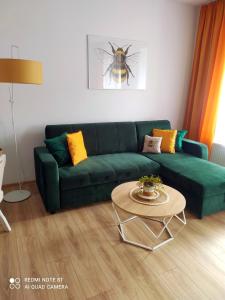 a living room with a green couch and a table at Apartament Miodownik in Międzylesie