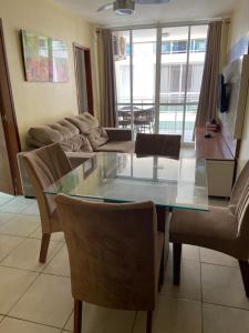 sala de estar con mesa de cristal y sillas en Apto na prainha- arraial do cabo, en Arraial do Cabo