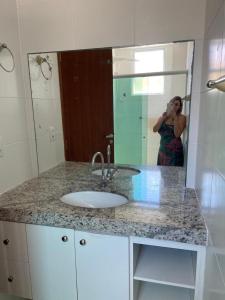 una mujer tomando una foto de un lavabo en un baño en Apto na prainha- arraial do cabo, en Arraial do Cabo