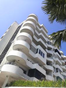 a white building with balconies and palm trees at 7 pool condo opposite the train station near old city and Nimman in Chiang Mai
