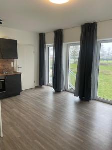 a living room with two large windows and a television at Boardinghouse Twistringen in Twistringen