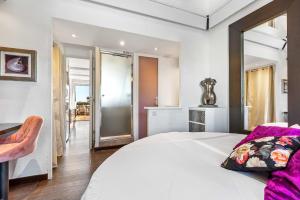 um quarto com uma grande cama branca com almofadas cor-de-rosa em La vie en rose naturiste - Port Nature em Cap d'Agde