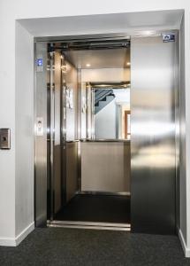 an elevator door in a building with a mirror at The Originals City, Hôtel Mulhouse Est in Rixheim