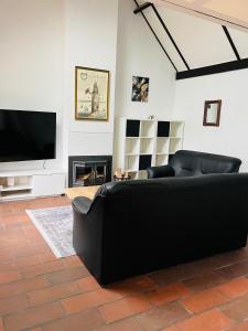 a living room with a black couch and a flat screen tv at Vissershuisje 6 te Koksijde in Koksijde