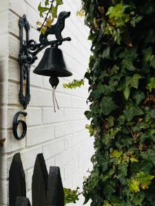 a bell hanging on a wall next to a ivy at Vissershuisje 6 te Koksijde in Koksijde