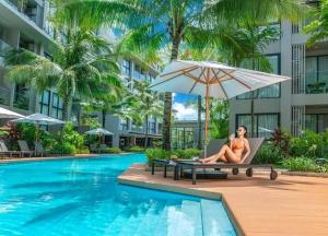 a couple sitting on a chair next to a swimming pool at Daimond Exclusive Junior Suite Bangtau Beach in Bang Tao Beach