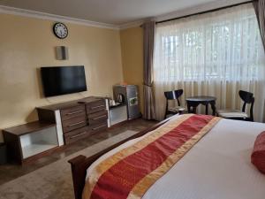 a hotel room with a bed and a flat screen tv at Asyana Gardens in Nairobi