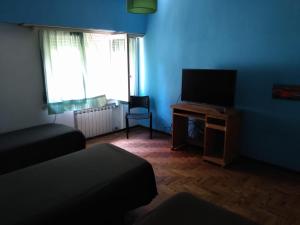 Alquiler Temporada Casa La Perla Para 8 Personas a 9 Cuadras de La Costa في مار ديل بلاتا: غرفة زرقاء مع سرير وتلفزيون