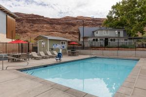 a swimming pool with chairs and a house at Sun Outdoors North Moab in Moab