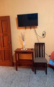 a tv on a wall with a table and a chair at Hotel Maya America in Panajachel