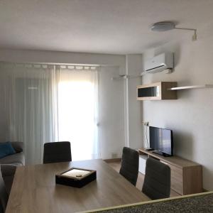 a living room with a table with chairs and a television at Beta's Beach in Blanes