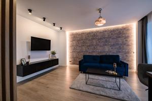 un salon avec un canapé bleu et une télévision dans l'établissement BRAVISA Apart View, à Braşov
