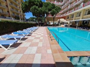 a row of lounge chairs next to a swimming pool at Beta's Beach in Blanes