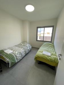2 łóżka w małym pokoju z oknem w obiekcie משהו בהגושרים- אירוח בגליל w mieście Ha-Goszerim