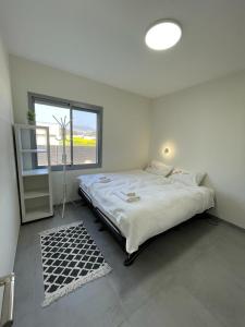 ein weißes Schlafzimmer mit einem großen Bett und einem Fenster in der Unterkunft משהו בהגושרים- אירוח בגליל in HaGoshrim