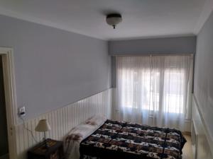 Alquiler Temporada Casa La Perla Para 8 Personas a 9 Cuadras de La Costa في مار ديل بلاتا: غرفة نوم بها سرير ونافذة بها ستارة