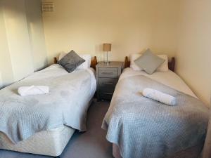 dos camas sentadas una al lado de la otra en una habitación en St Ives, King Bed Cosy home, parking, fast Wi Fi, en St Ives