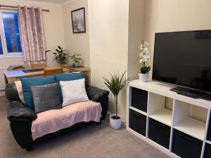 uma sala de estar com um sofá e uma televisão de ecrã plano em St Ives, King Bed Cosy home, parking, fast Wi Fi em St Ives