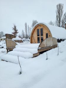 eine Holzhütte im Schnee mit schneebedeckten Bänken in der Unterkunft La cabane de l'étang 
