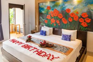 Dewangga Ubud في أوبود: غرفة نوم بسريرين عليها ورد احمر