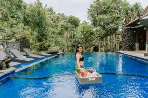 una donna in piedi in acqua accanto a una piscina di Dewangga Ubud ad Ubud