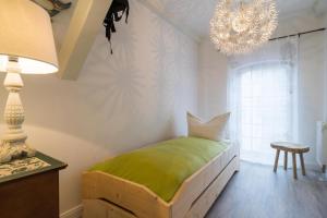 a bedroom with a green bed and a chandelier at Villa Bellevue 3 _App_ 12 in Ahlbeck +4 photos