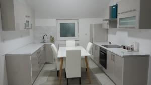 eine weiße Küche mit einem Tisch und Stühlen in der Unterkunft Apartman XXL in Brčko