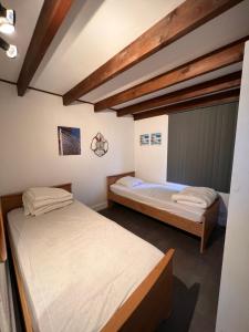 two beds in a room with wooden ceilings at Zeegalm Bungalows in Middelkerke
