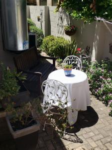 a table and chairs in a garden with a vase on it at Hermanus Sea view room in Hermanus +15 photos