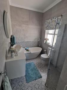 uma casa de banho com uma banheira, um lavatório e um WC. em Hermanus Sea view room em Hermanus