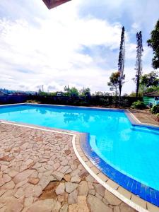 a large swimming pool with blue water in a yard at Fania Villa in Cinengangirang
