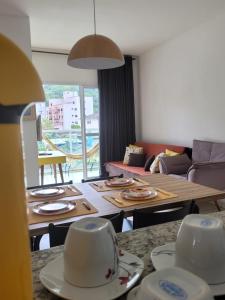 una sala de estar con una mesa con platos. en Apartamento Guarujá Lazer completo Villa Di Fiori 600mts da praia, en Guarujá