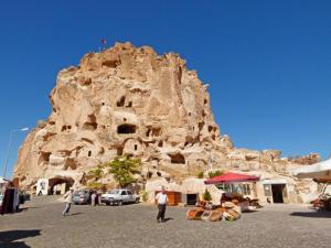 a large rock mountain with people standing in front of it at Sandık cave suites in Nevsehir