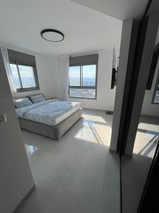 a bedroom with a bed in a room with windows at luxury condo in Qiryat Motzkin