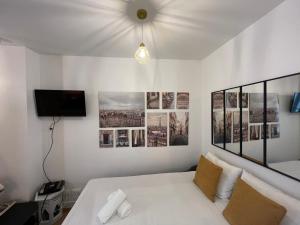 a bedroom with a white bed and pictures on the wall at EXPOSITION APPARTEMENT in Paris