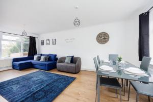 a living room with a table and a blue couch at Ebony Door Serviced Accommodation Barking Riverside in Barking