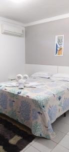ein Schlafzimmer mit einem Bett mit einer blauen und weißen Decke in der Unterkunft POUSADA VENTO NORTE CAMA & CAFÉ SUÍTES INDIVIDUAIs in João Pessoa