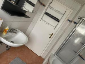 ein weißes Bad mit einem Waschbecken und einer Dusche in der Unterkunft Ferienwohnung in Gattendorf