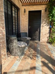 Un patio con dos sillas y una mesa y una puerta. en Casa completa a 3 cuadras de la playa del Sheraton y metros de la Plaza de Toros, en Colonia del Sacramento