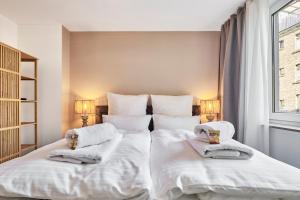 een slaapkamer met een groot bed met witte lakens en handdoeken bij Park Avenue - Design Apartment Friesenstraße - 4 Pers - WLAN - Netflix - 65 Zoll TV in Keulen