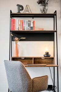 a bookshelf with a chair and a shelf with books at Park Avenue - Design Apartment Friesenstraße - 4 Pers - WLAN - Netflix - 65 Zoll TV in Cologne