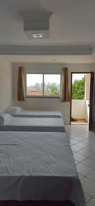 - une chambre avec 2 lits et une grande fenêtre dans l'établissement Pousada Ponta Negra, à Natal
